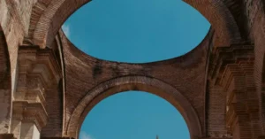 Elegant ancient brick arches of a historic ruin in Antígua, Guatemala, under a clear blue sky.