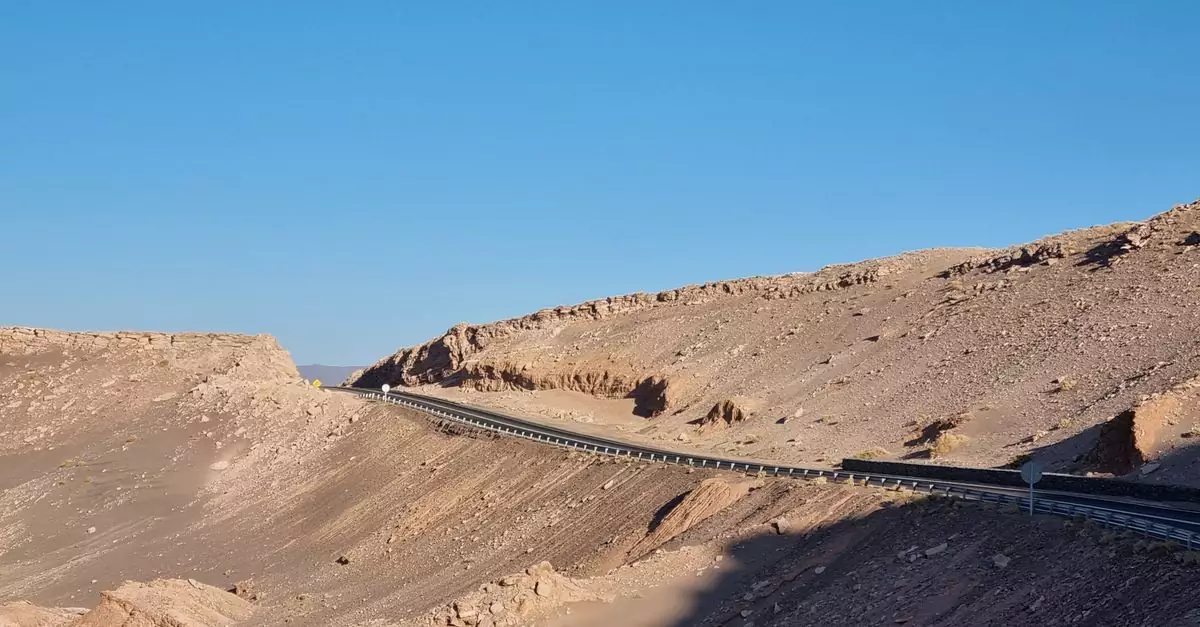 A stunning view of a road winding through the arid terrain of the Atacama Desert under a clear blue sky.