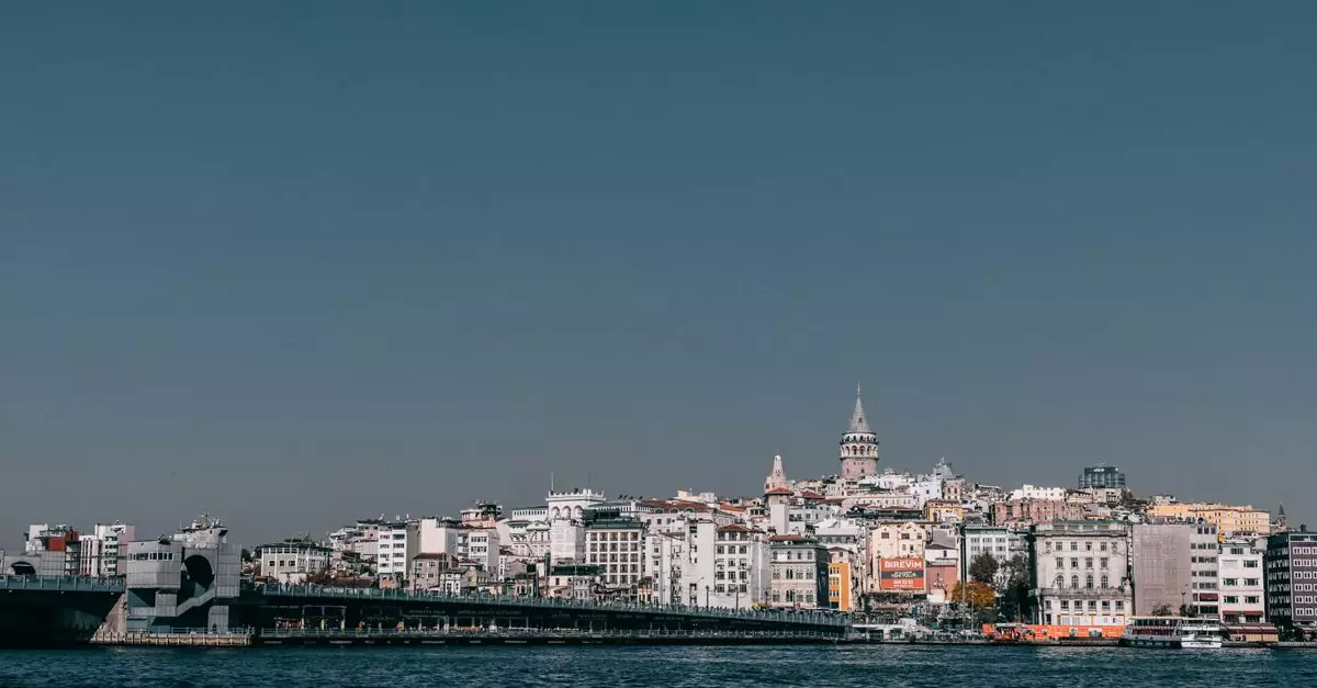 Modern bridge crossing calm sea against residential building and Galata tower of coastal city in Istanbul in turkey against blue sky