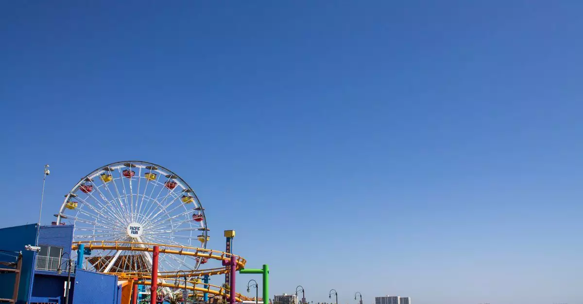 Bright day at Santa Monica Pier featuring the iconic Pacific Park Ferris Wheel against a clear blue sky.
