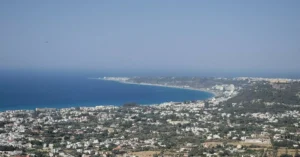 Stunning aerial view of a coastal cityscape and azure sea in Greece on a sunny day.