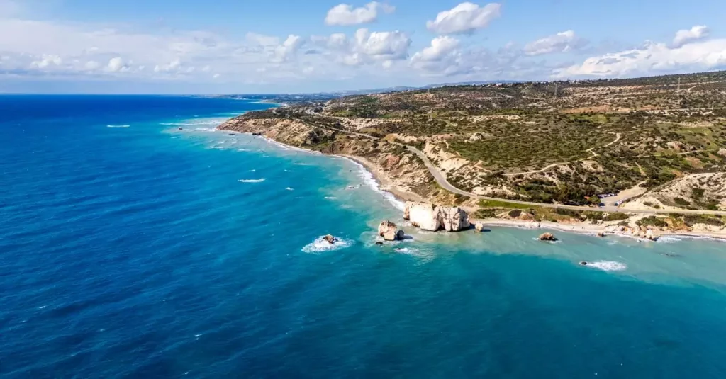 Stunning aerial photograph of Aphrodite's Rock on Cyprus coastline, surrounded by vibrant blue waters.