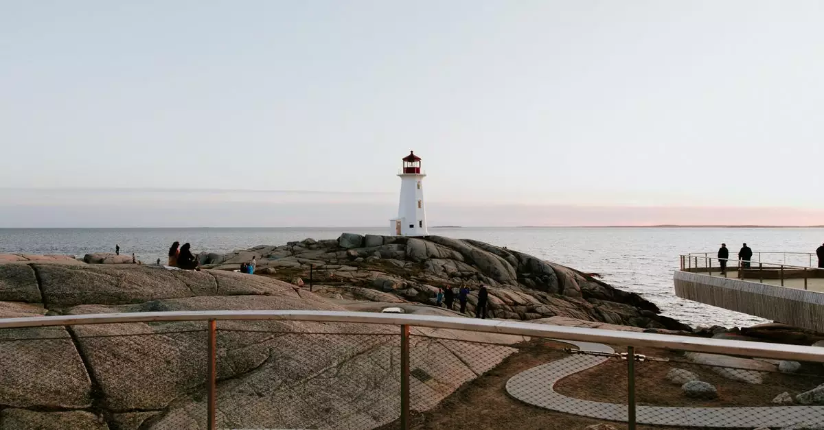 Capture of Peggy's Cove Lighthouse during twilight with visitors on the rocky shore.
