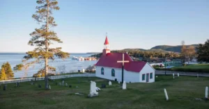 Charming church with a red roof overlooking scenic Tadoussac Bay in Québec, Canada.