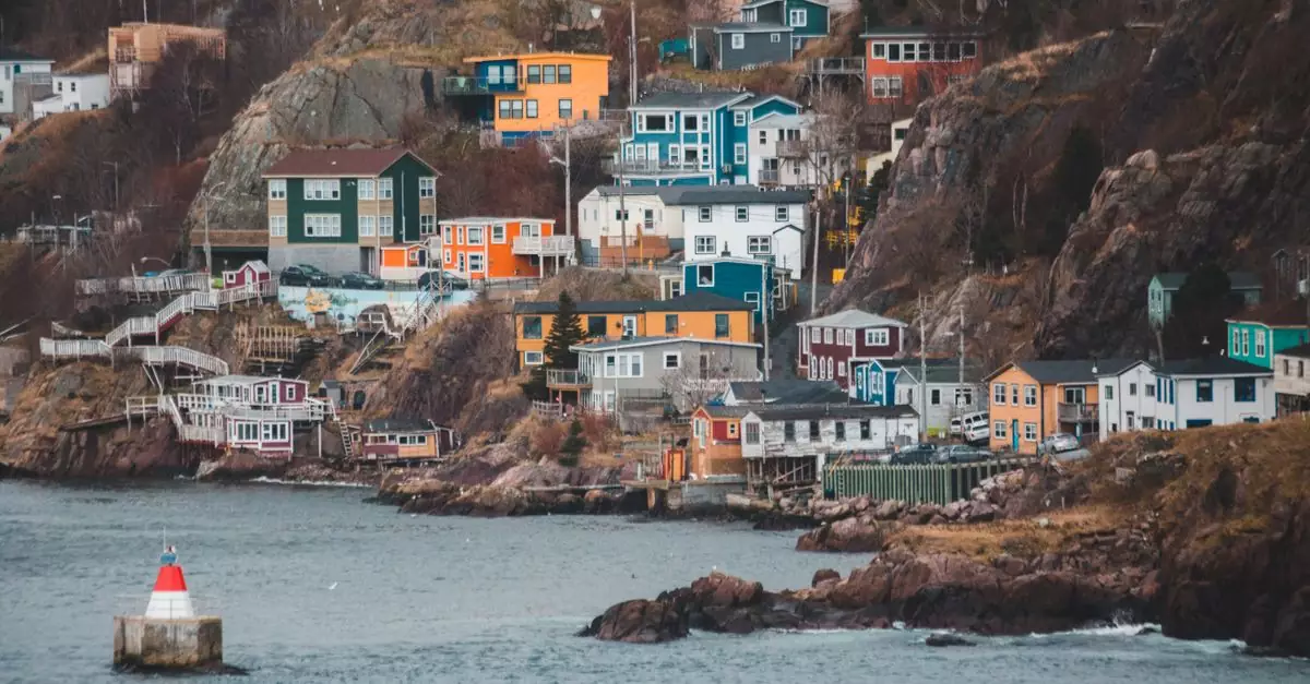 Contemporary dwelling building exteriors on mountain against rippled ocean with buoy in town in daytime