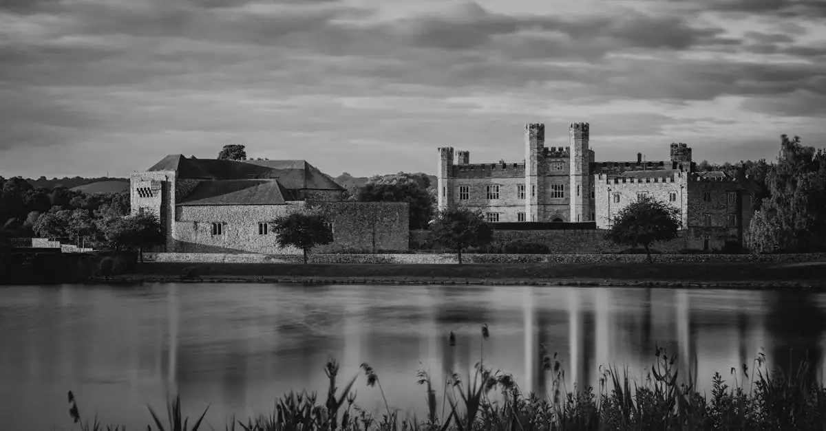 Black and white photo of Leeds Castle reflected in a lake under a cloudy sky.
