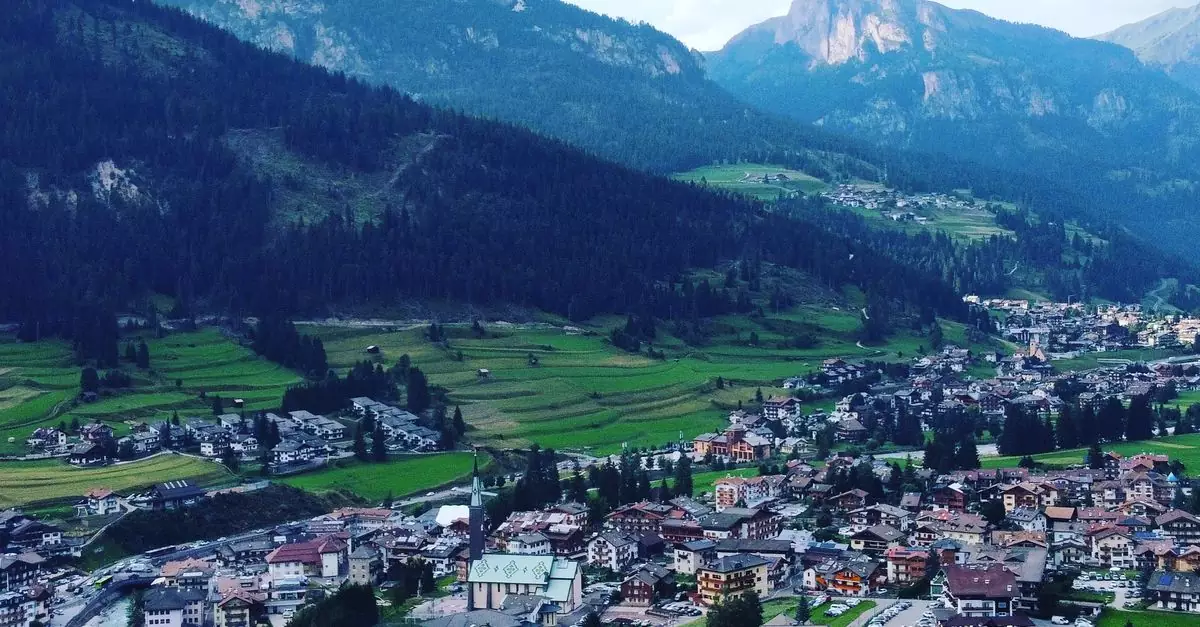 A picturesque view of Pozza di Fassa village surrounded by the Dolomites mountains in summer.