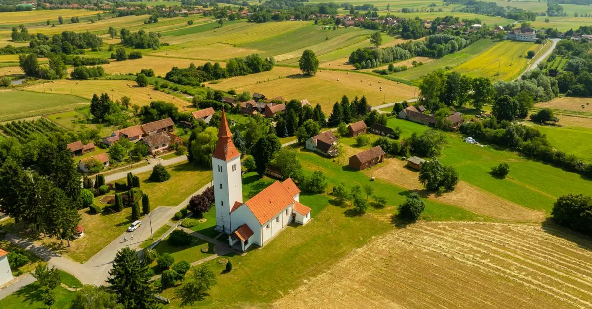 Aerial shot of a rural church surrounded by fields in Velika Trnovitica, Croatia.