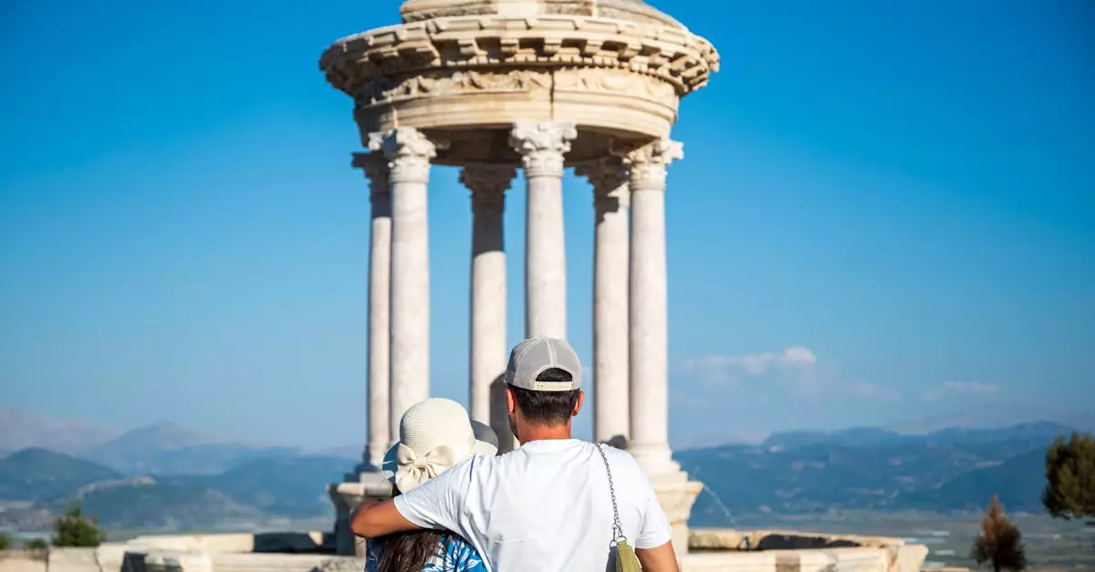 A couple embraces while admiring an ancient temple under a clear blue sky.