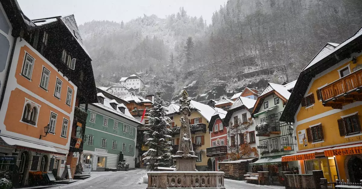 Charming winter view of Hallstatt's colorful town square with snow-covered buildings and a central fountain.