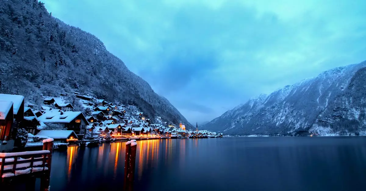 Captivating winter landscape of Hallstatt with illuminated houses and snow-covered mountains at twilight.