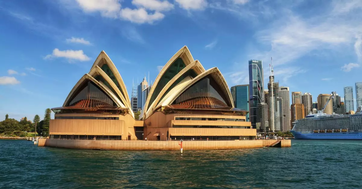Iconic Sydney Opera House in Sydney Harbour with city skyline on a sunny day.