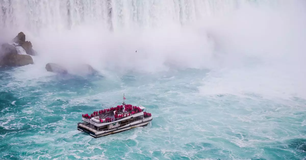 From above of yacht with anonymous tourist sailing on rippled river near rapid splattering cascade