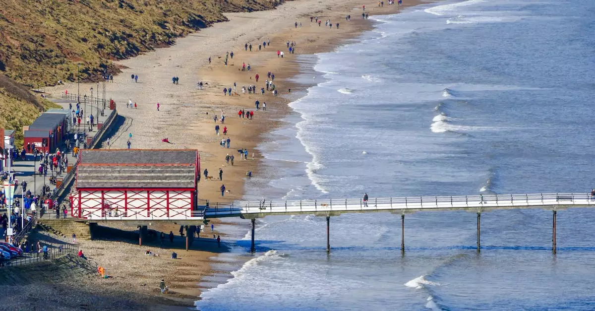 Aerial view of Saltburn-by-the-Sea's pier and beach with visitors enjoying a sunny day.