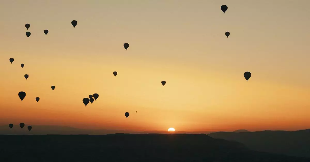 Silhouettes of hot air balloons over Cappadocia at sunrise, offering a serene travel experience.