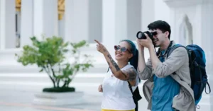 A smiling man and woman explore architectural landmarks with a camera, embracing travel and photography.