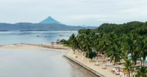 Aerial view capturing the scenic beauty of Mayon Volcano and the tropical coastline in Legazpi City, Philippines.