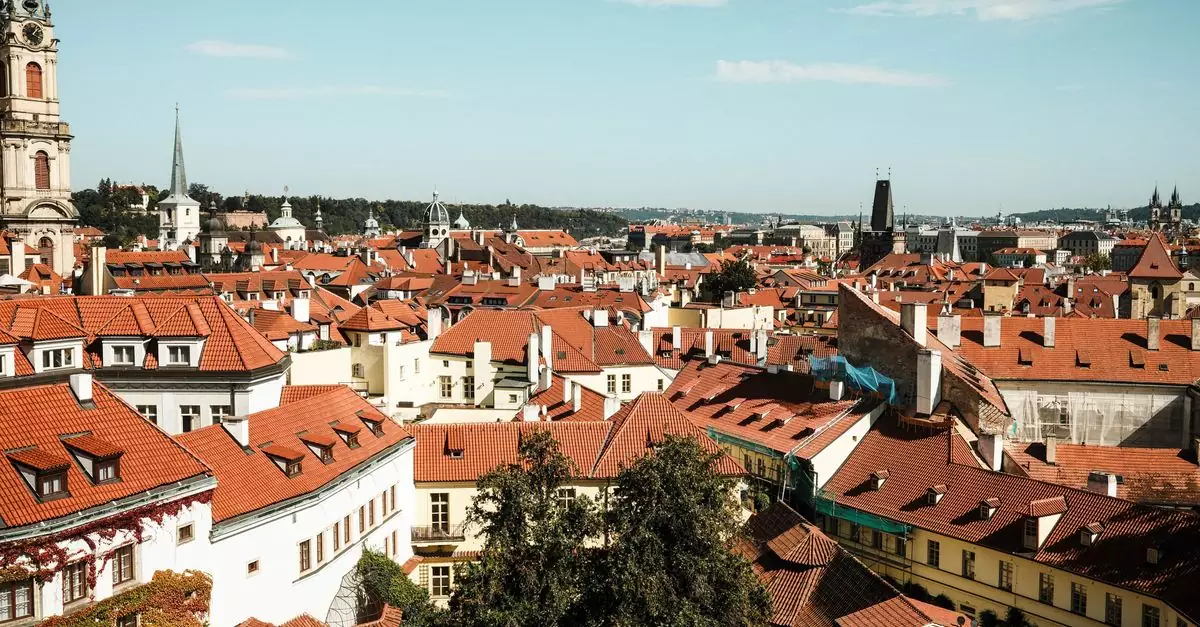 Explore the charming red-tiled rooftops of Prague's historic district under a clear blue sky.
