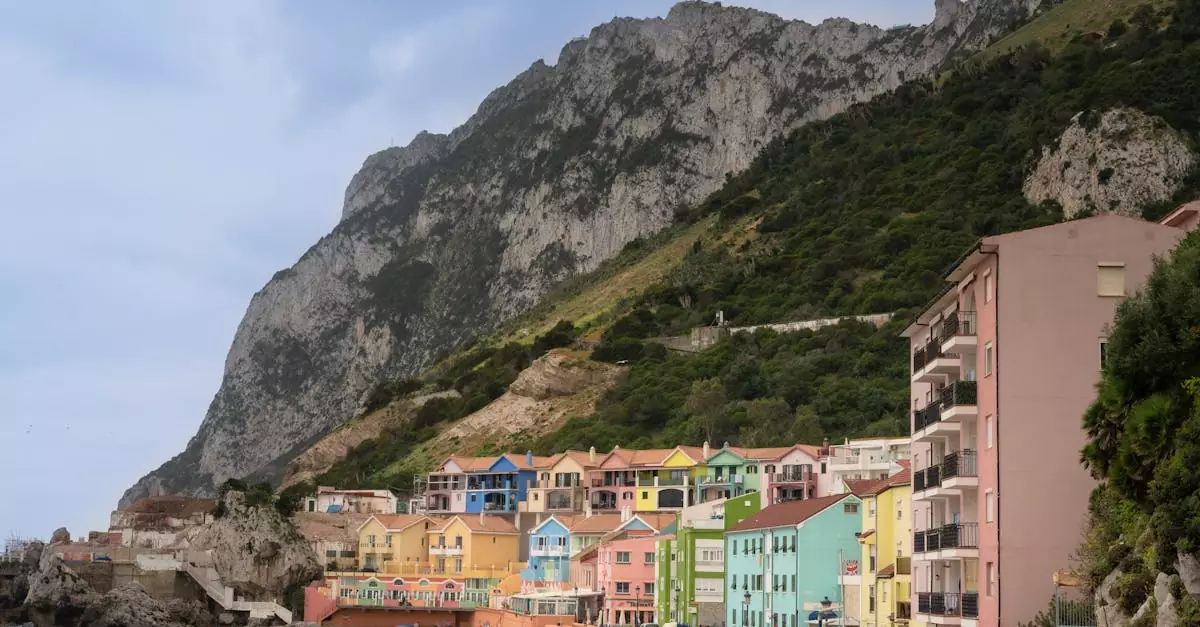 Colorful buildings line the beach with the towering Rock of Gibraltar in the backdrop.