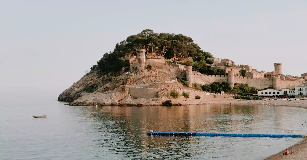 Beautiful view of a medieval castle on the Costa Brava coast with calm sea and sandy beach.