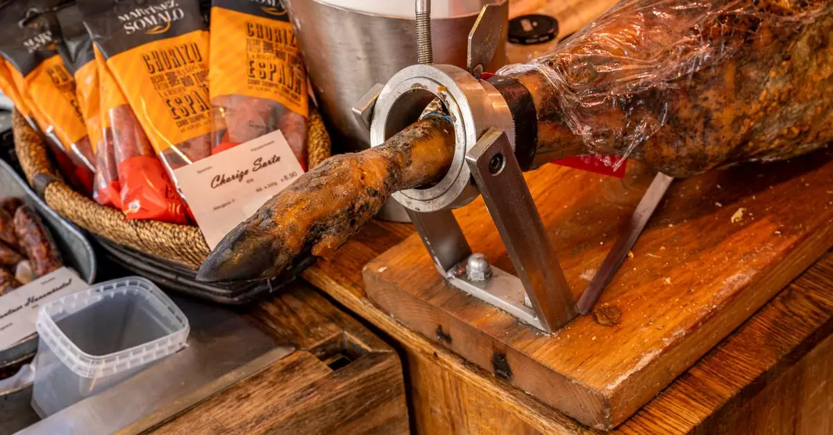Close-up of cured meats including Spanish ham and chorizo in a gourmet shop display.