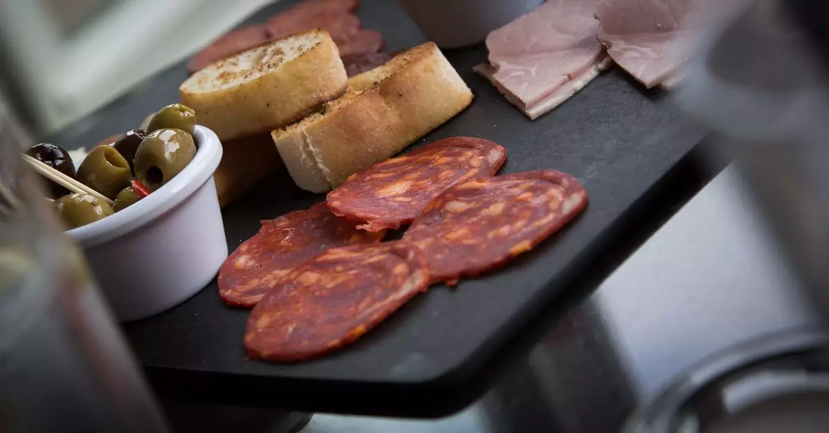 A delicious charcuterie platter featuring salami, ham, olives, and sliced bread on a slate board.