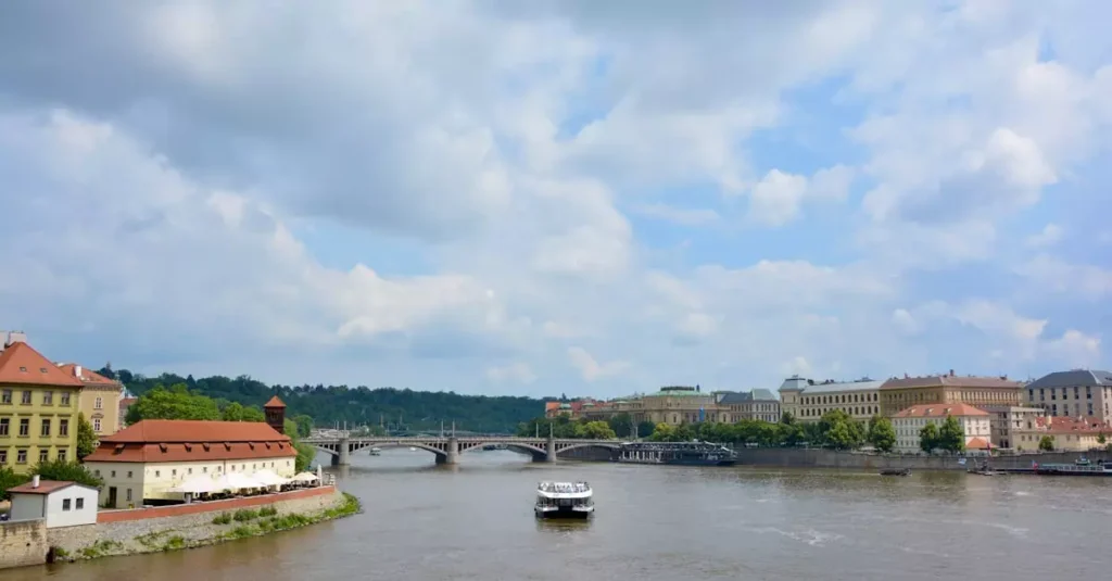 A serene day on the Vltava River in Prague surrounded by historic architecture and lush greenery.