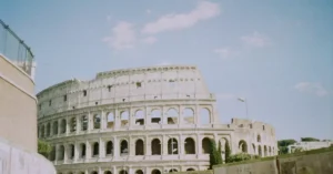 View of the iconic Colosseum in Rome, Italy, on a sunny day with tourists exploring the landmark.