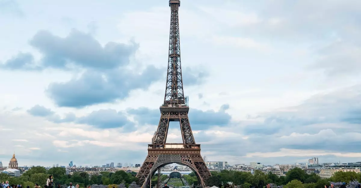 Iconic view of the Eiffel Tower in Paris surrounded by tourists on a cloudy day.