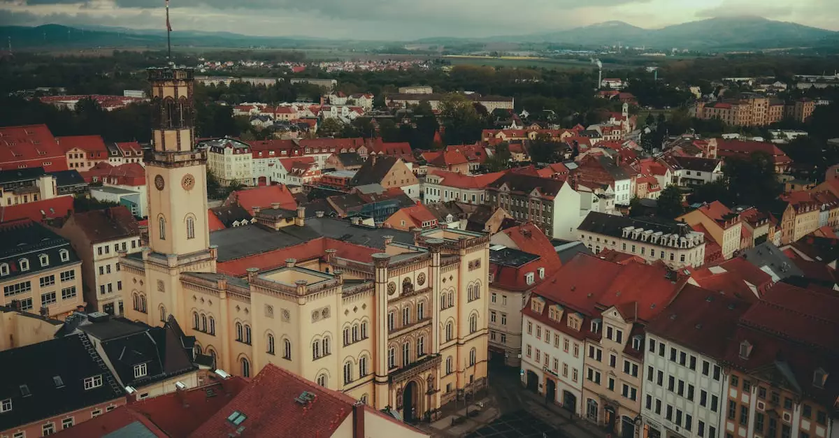 Drone shot of Zittau Town Hall surrounded by red-roofed buildings under cloudy skies.
