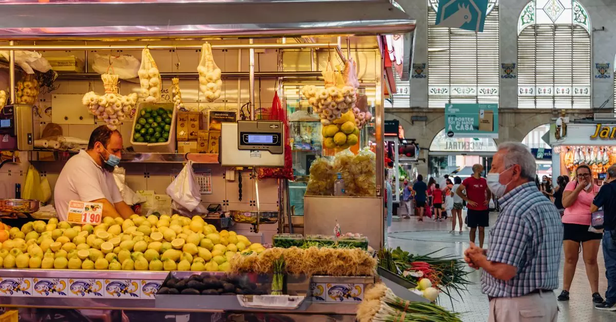 A bustling market stall in Valencia, Spain with fresh produce and people shopping.