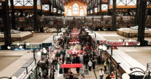 Explore the vibrant Budapest Central Market Hall filled with shoppers and vendors captured from above.