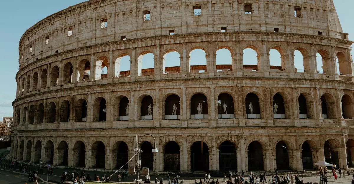 Iconic Colosseum in Rome captured on a sunny day with tourists exploring the ancient structure.