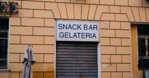 Facade of a snack bar and gelateria in Rome, Italy. Urban architecture with a closed shutter.