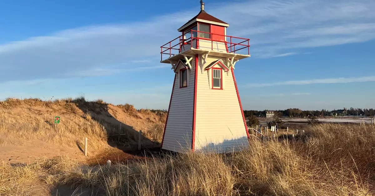 Rustic Covehead Harbour Lighthouse in Prince Edward Island, surrounded by dunes under a clear sky.