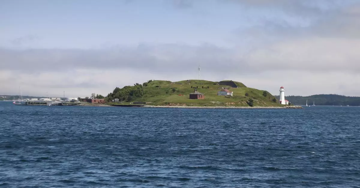 Scenic view of an island with a lighthouse surrounded by blue sea under a partly cloudy sky.