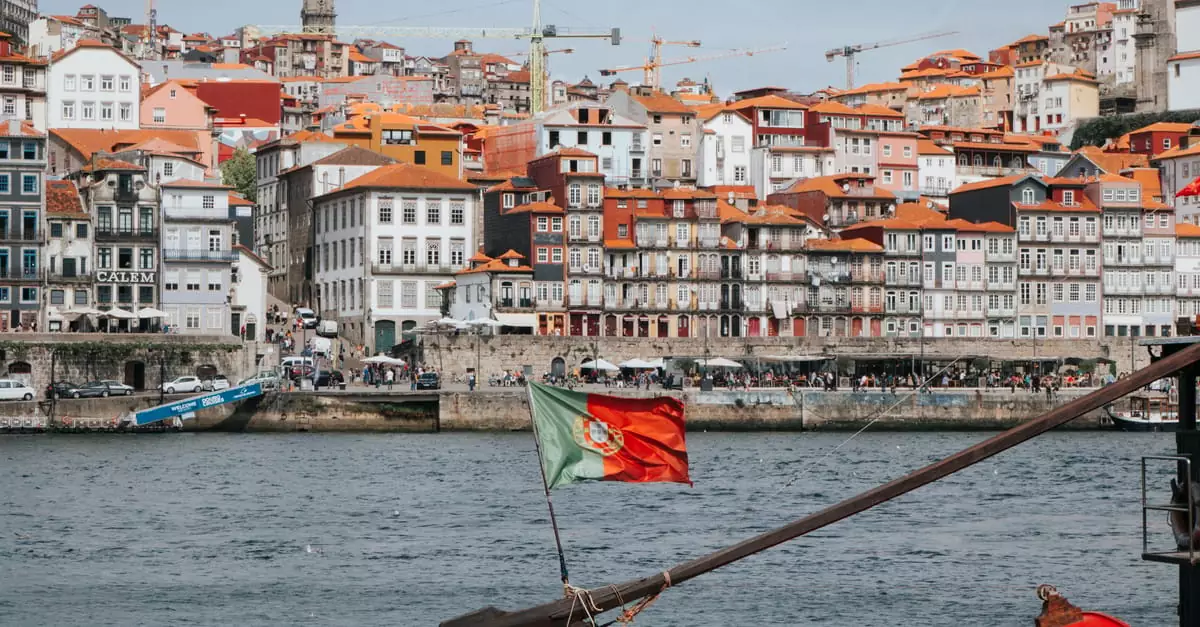 Colorful Ribeira District in Porto with Douro River and traditional Rabelo boat.