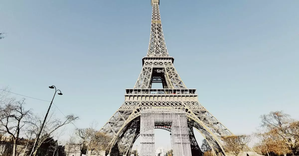 Low angle shot of the Eiffel Tower in Paris with blue sky and partial park view.