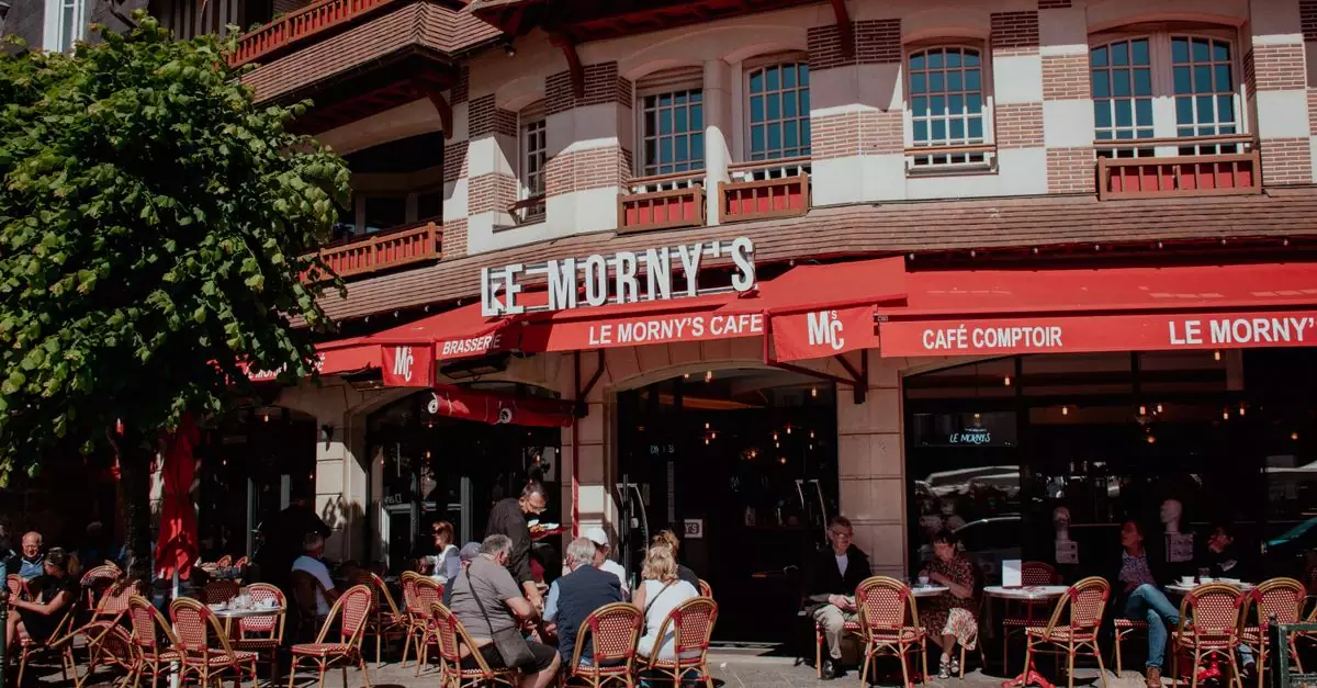 Charming street view of Le Morny's Caf&eacute; in Deauville with people enjoying outdoor seating.