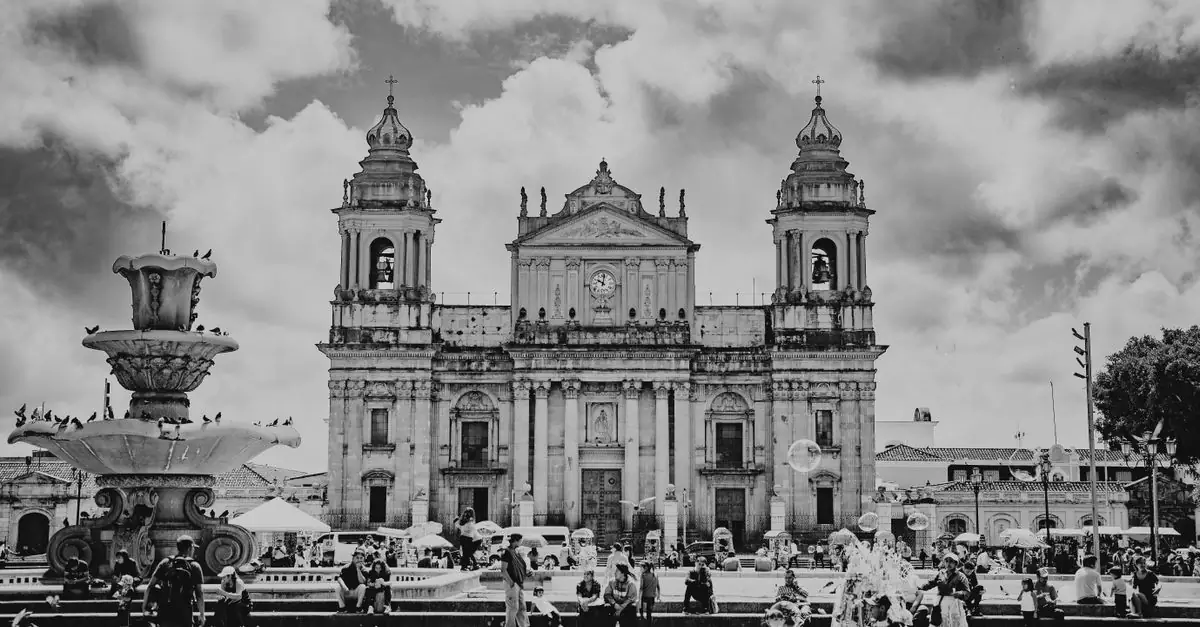 Dramatic black and white photo of Guatemala City's historic cathedral with urban activity.