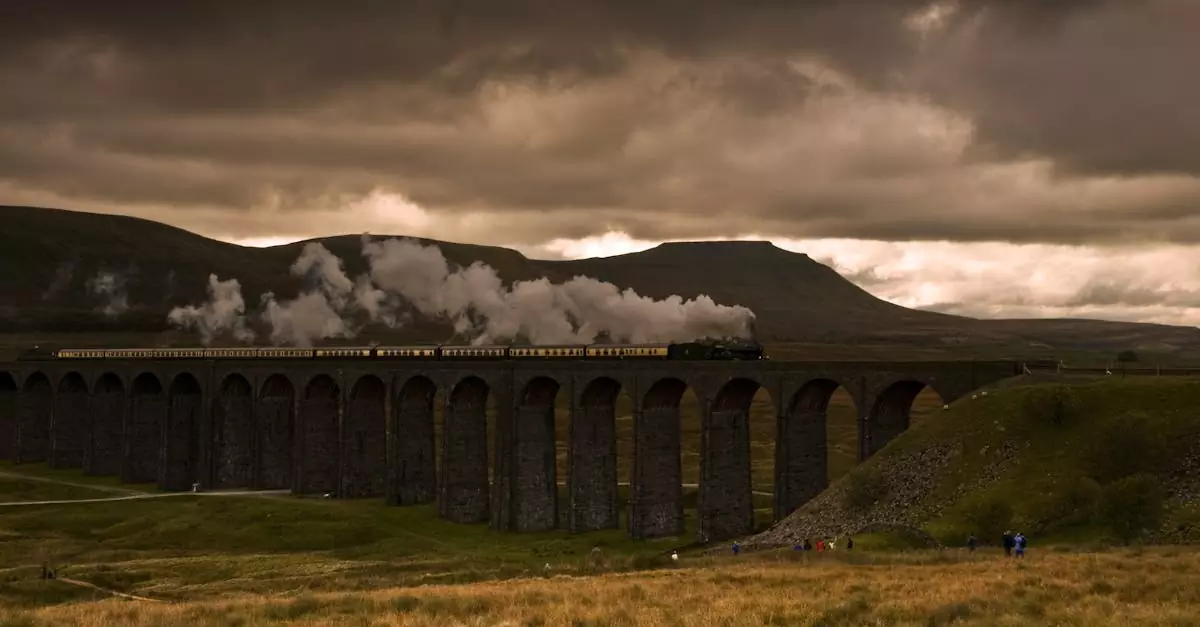 A steam train crosses a picturesque viaduct against a dramatic sky.