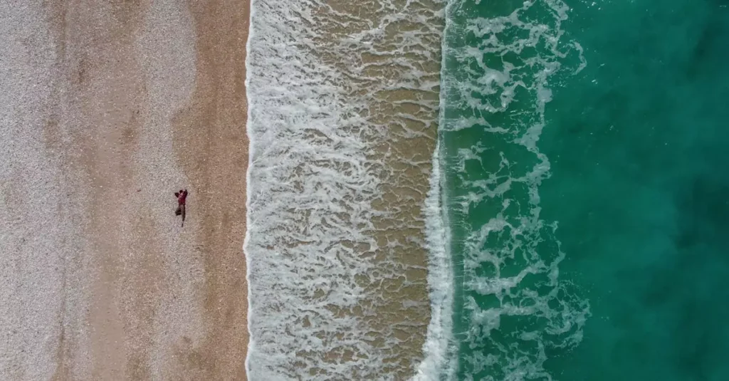 Europe's Best Hidden Beaches: Secluded Shores Guide 5 Explore the stunning aerial view of Borsh Beach, Albania with waves crashing on the shore.