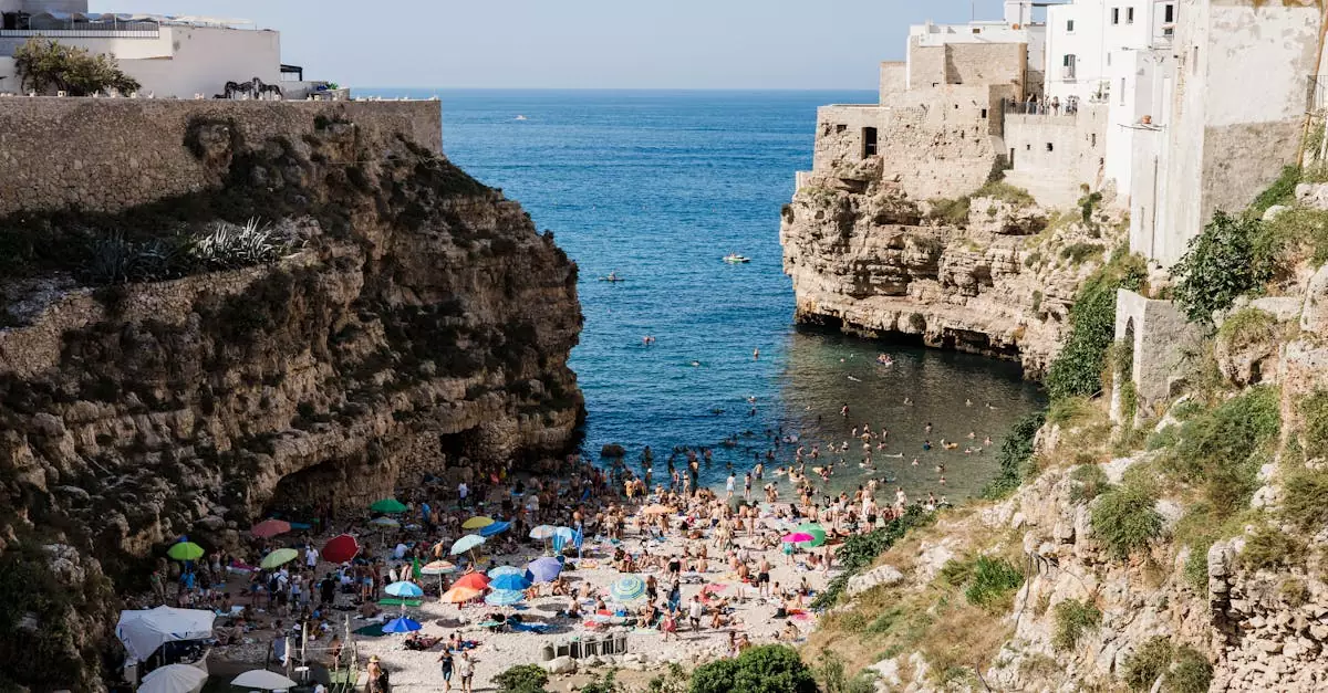 A vibrant summer scene at Lama Monachile beach in Polignano a Mare, Italy, showcasing cliffs and lively tourists.