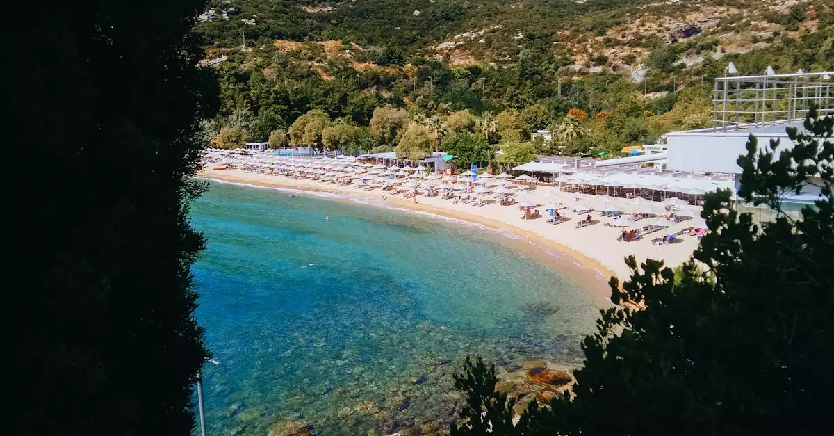 A vibrant seaside resort featuring a sandy beach with umbrellas and lush greenery.