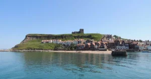 Picturesque view of Whitby beach with historic Abbey under a clear sky.
