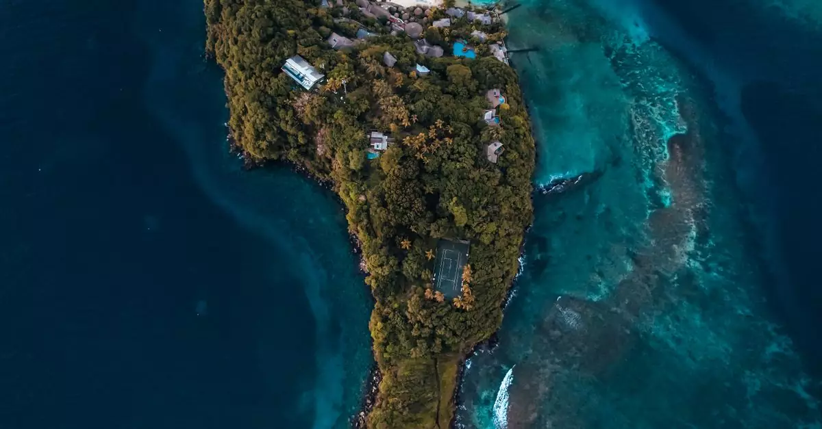 Stunning drone shot capturing a lush tropical island surrounded by vibrant blue sea.