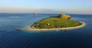 A stunning aerial view of a serene island in West Nusa Tenggara, Indonesia, surrounded by clear blue waters.