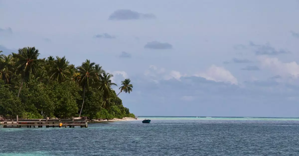 Serene view of a tropical island with lush palm trees and a lone boat on the turquoise sea.