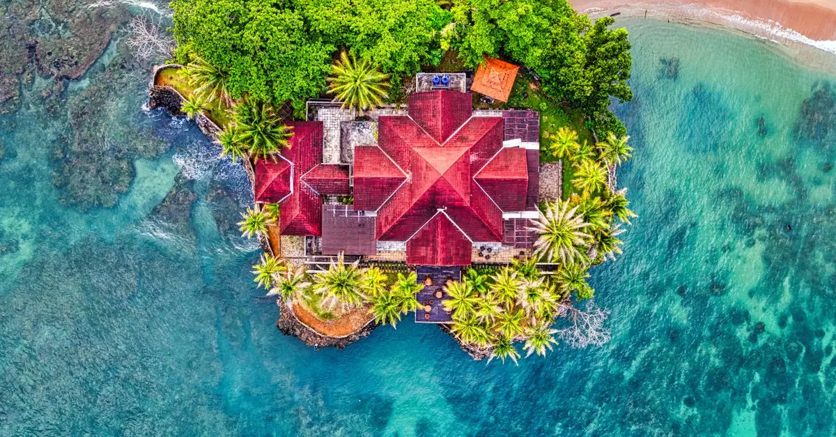 Stunning aerial shot of a house surrounded by turquoise water and lush greenery in Banten, Indonesia.