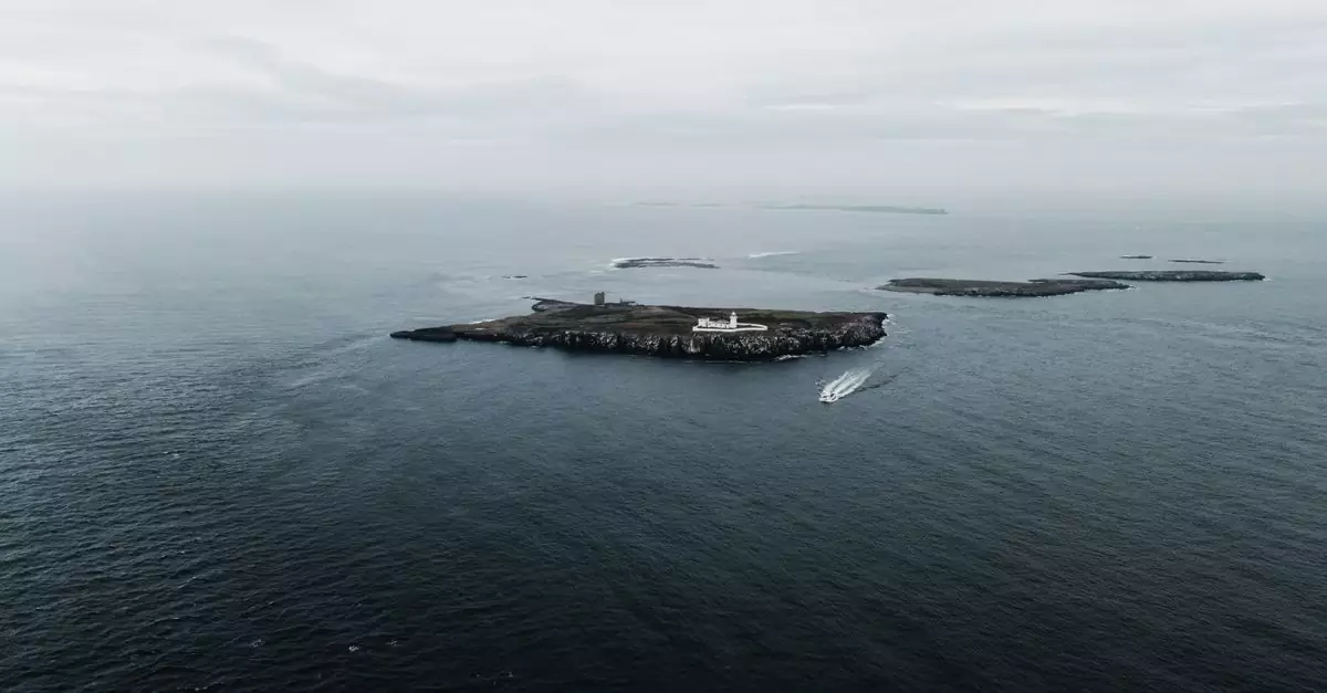 Drone shot capturing the serene Farne Islands and lighthouse in the UK sea.
